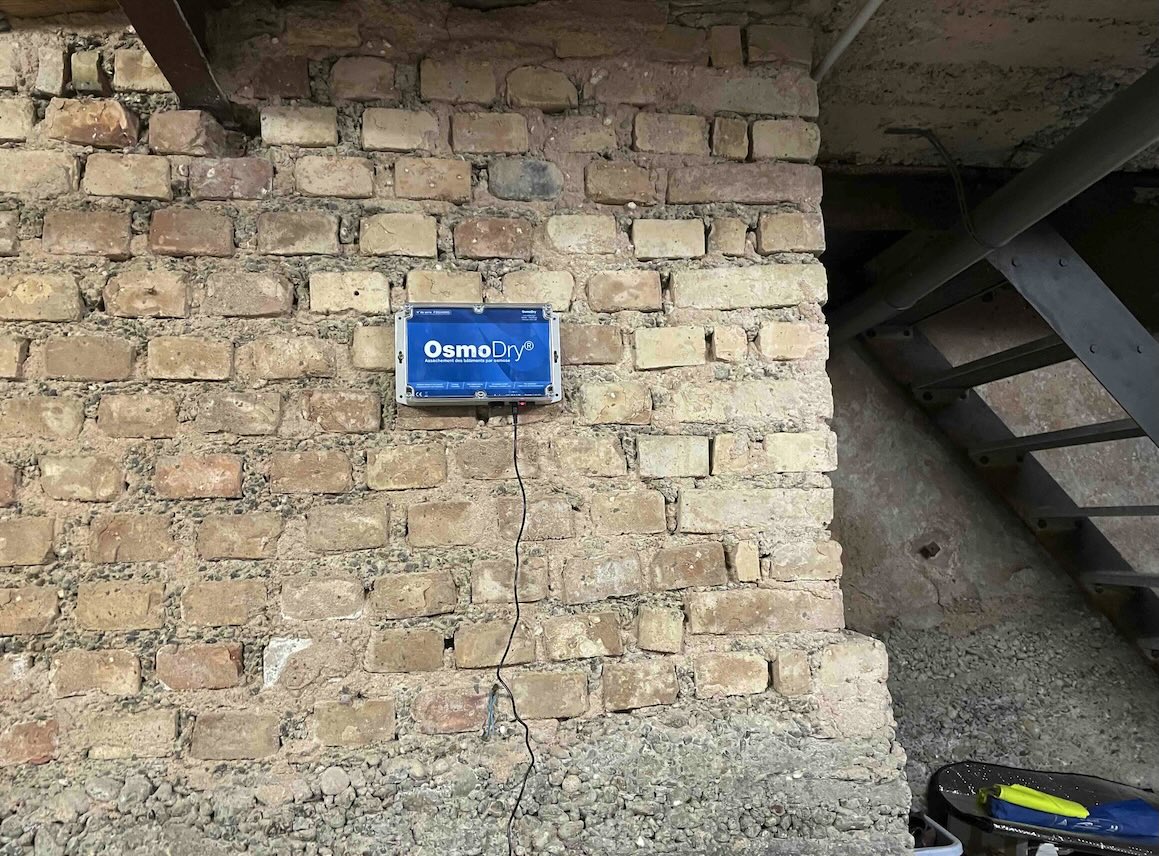 Boîtier OsmoDry® posé sur mur en briques — cave Alsace